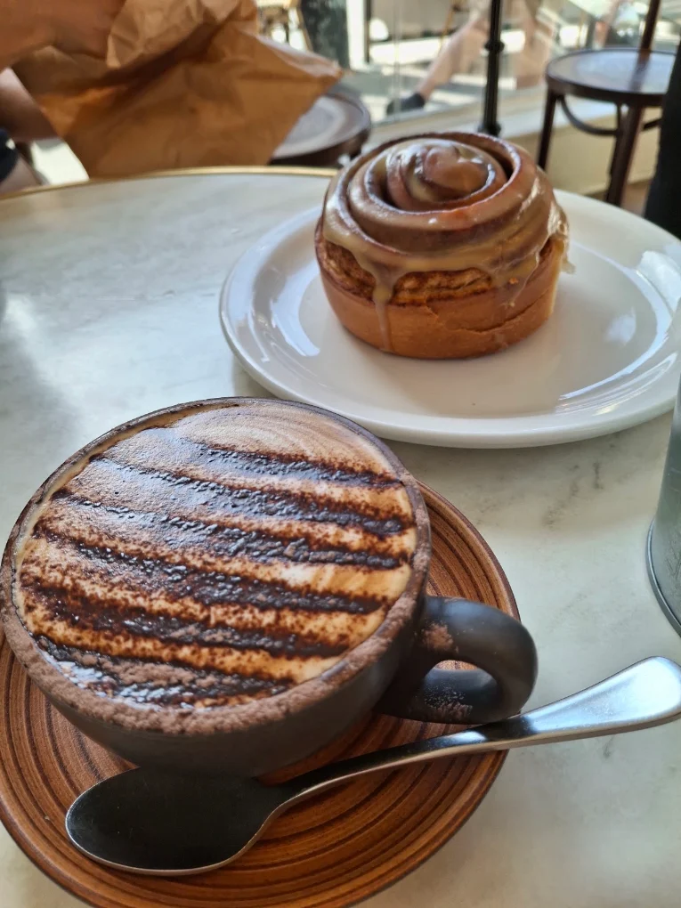 Cinnamon scroll served with a hot chocolate on a cafe table