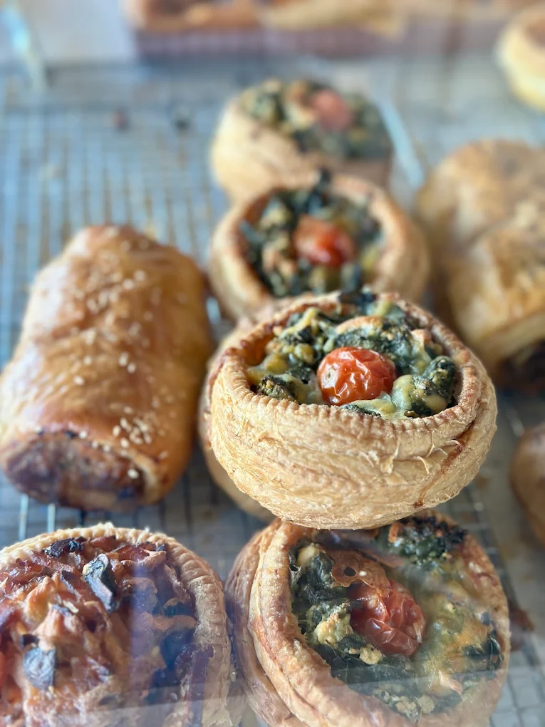 Sausage roll and savoury vegetable tarts cooling on a rack